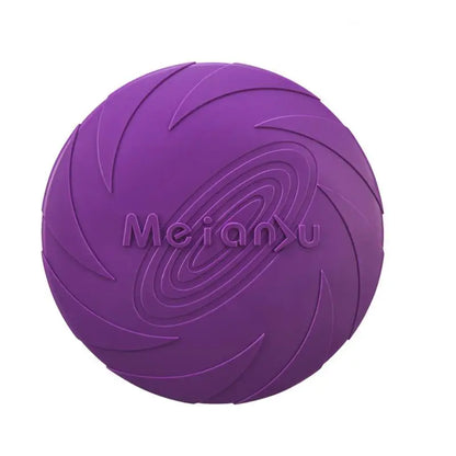 A dog catching a blue flying disc with more discs in orange and purple lying on the ground.